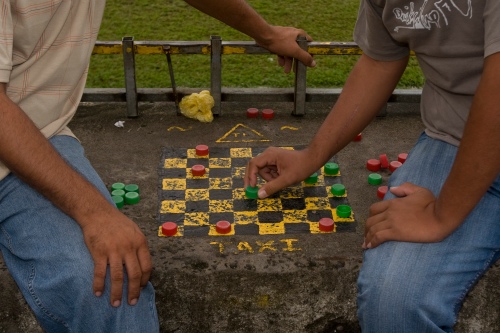 Conductores de Taxi juegan damas chinas en la plaza de Sarapiquí. Taxi drivers play checkers next to the Sarapiquí soccer field.